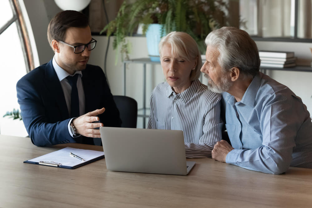 three professionals discussing over a laptop during a business meeting