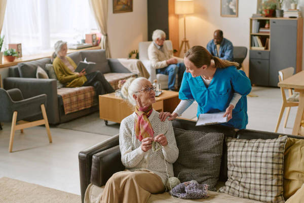 A caregiver interacting with a senior woman in a cozy living room setting.