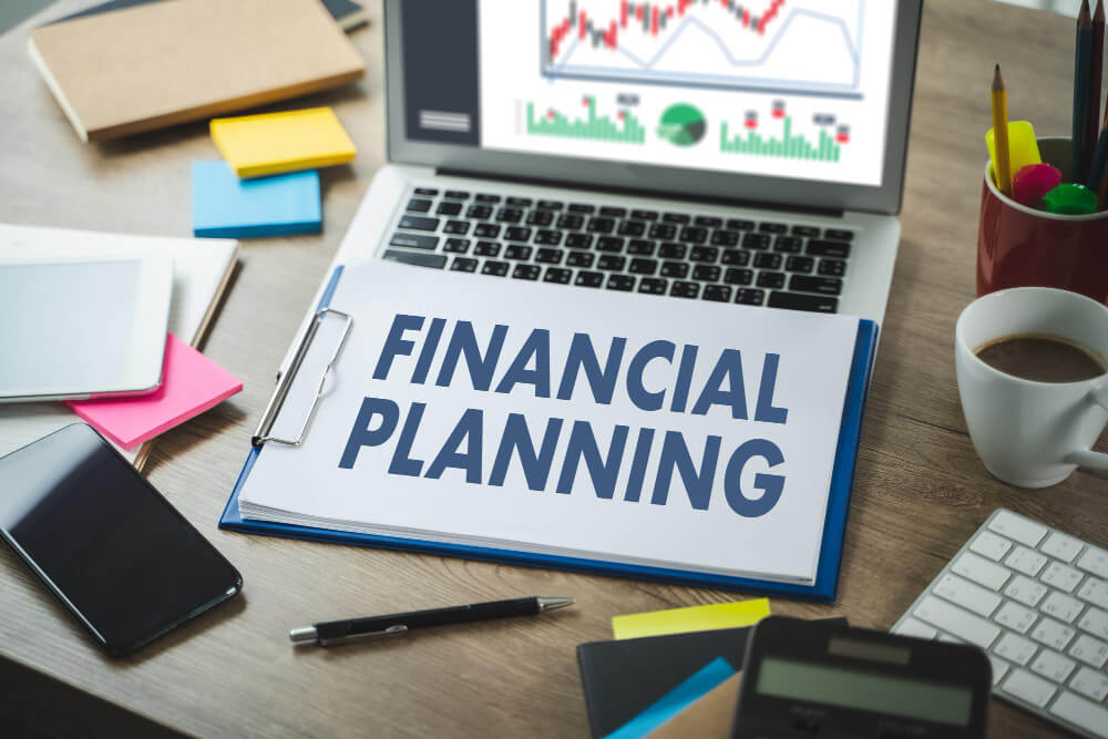 A workspace with financial planning materials, including a laptop and stationery.